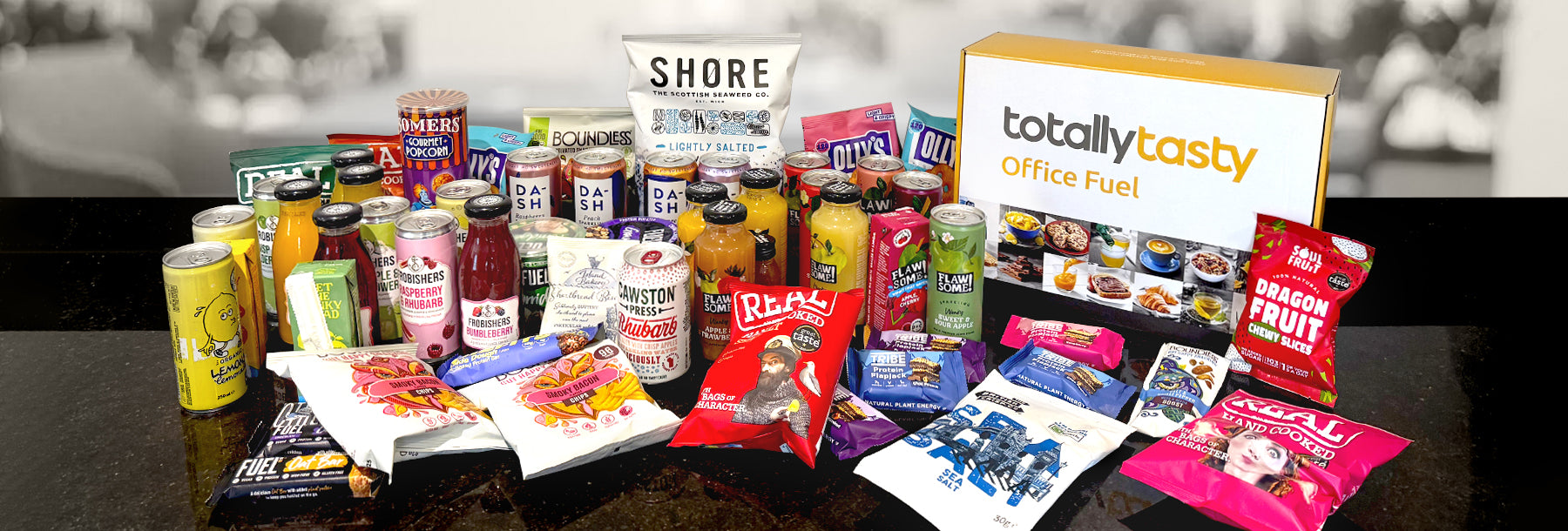 Assorted food products including snacks and drinks on a table with 'totallytasty' branding.