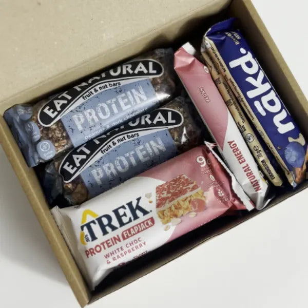 Box containing various protein bars from different brands on a light background