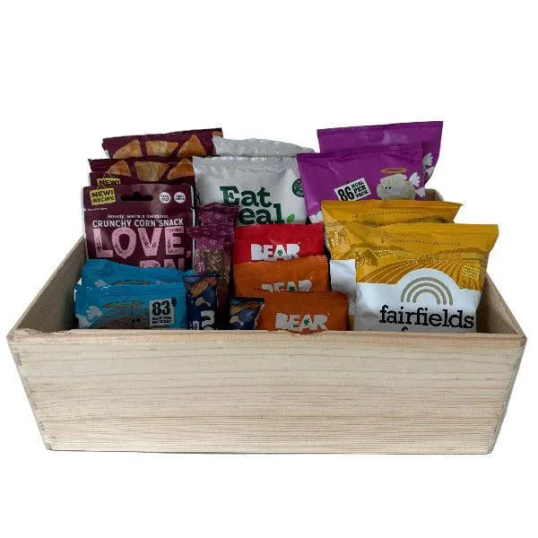 Assorted snack packets in a wooden box on a white background