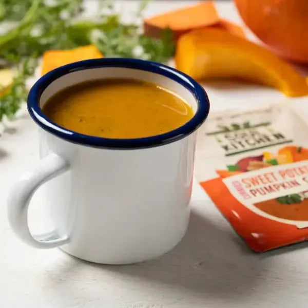 Mug of Soul Kitchen Curried Sweet Potato Pumpkin Soup with a Soul Kitchen packet in the background